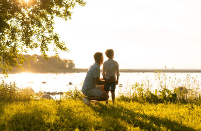 Father and his little son. Happy loving family walking outdoor in the light of sunset. Sea and field background