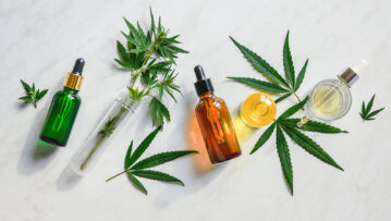 Different glass bottles with CBD OIL, THC tincture and cannabis leaves on yellow background. Flat lay, minimalism. Cosmetics CBD oil.