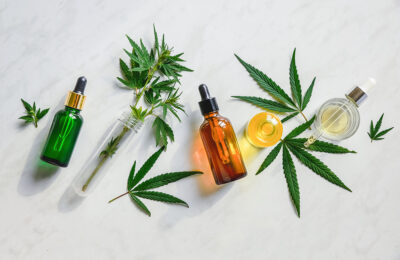 Different glass bottles with CBD OIL, THC tincture and cannabis leaves on yellow background. Flat lay, minimalism. Cosmetics CBD oil.