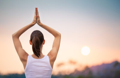 Woman meditating on the beach at sunset.